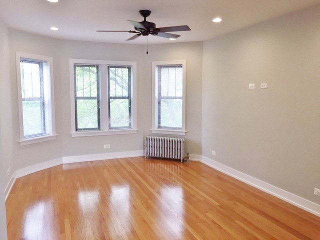an empty living room with wood floors and a ceiling fan