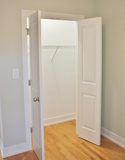 an empty closet with an open door and a closet door open to a white closet