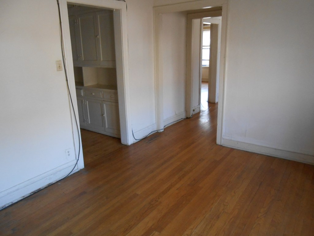 an empty living room and hallway with wooden floors and white walls