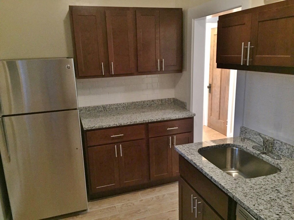 a kitchen with granite counter tops and a stainless steel refrigerator
