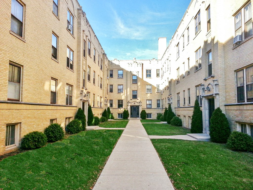 a view of an apartment complex with a sidewalk and green lawn