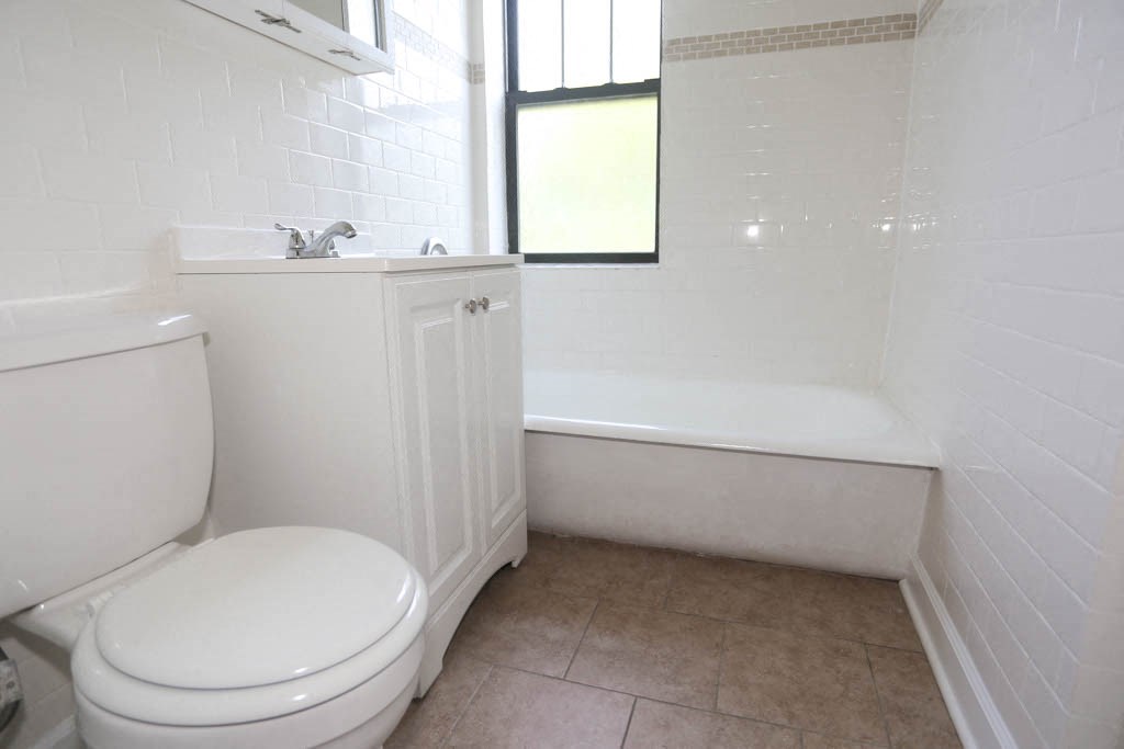 a bathroom with a toilet and a tub and a window