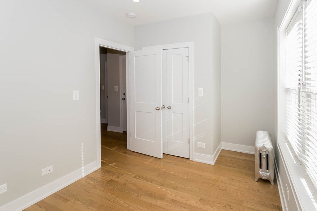 a bedroom with white doors and a wooden floor     and a closet
