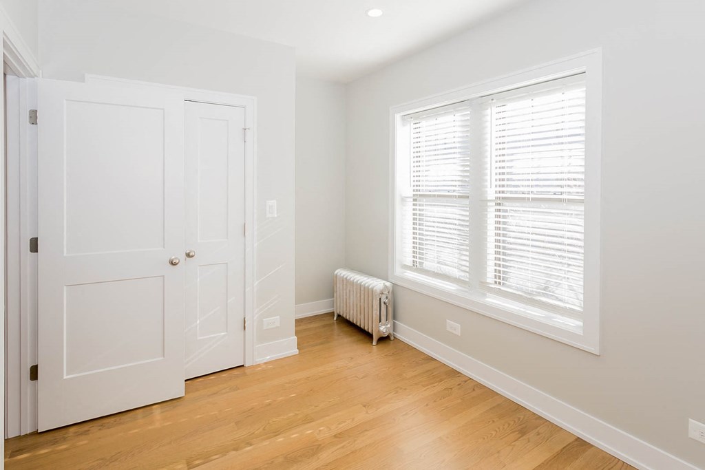 a bedroom with white walls and a window and a white door