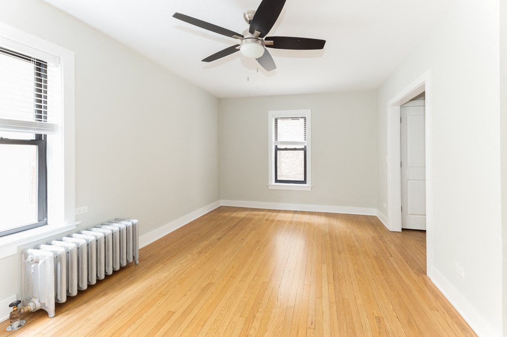 an empty room with a ceiling fan and a radiator