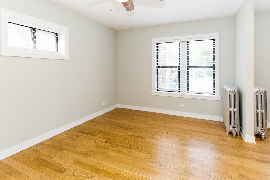 an empty room with wood floors and a window and radiator