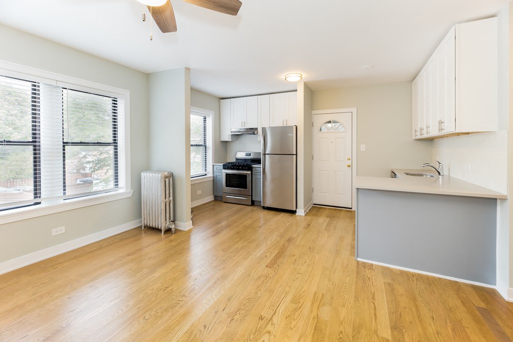 an empty kitchen with a large window and a stainless steel refrigerator