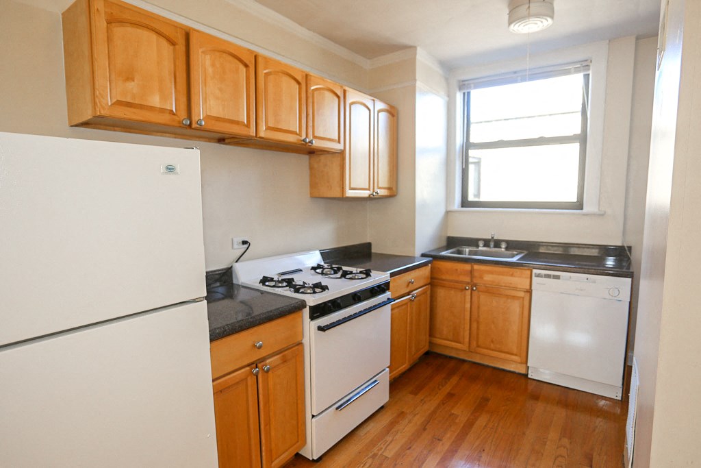an empty kitchen with white appliances and wooden cabinets