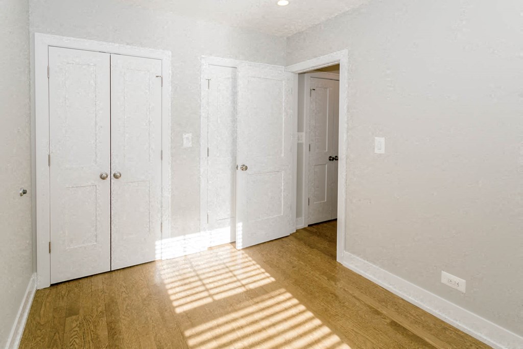 a bedroom with three closets and a door to a hallway