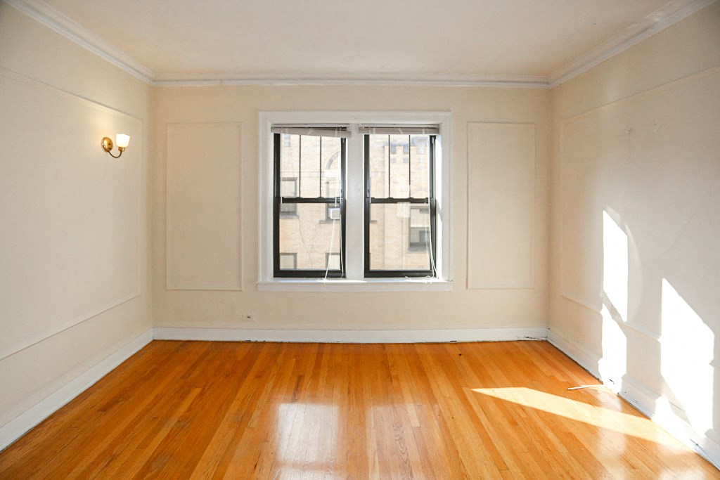 an empty living room with a window and wooden floors
