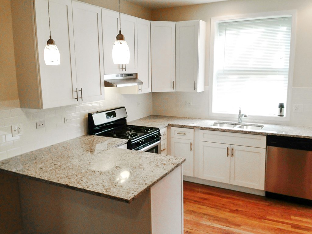 a kitchen with white cabinets and granite counter tops