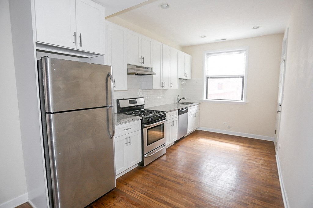 an empty kitchen with stainless steel appliances and white cabinets