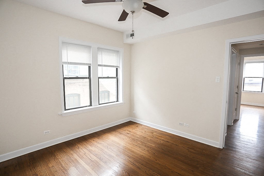 an empty living room with wood floors and a ceiling fan