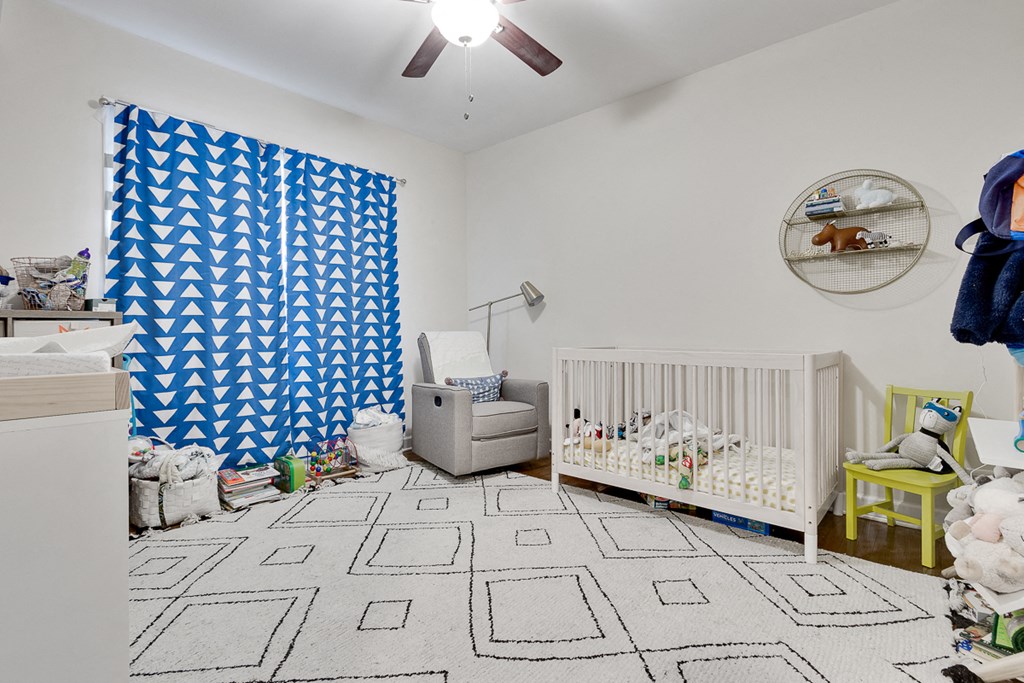 a baby room with a white crib and a blue and white patterned curtain