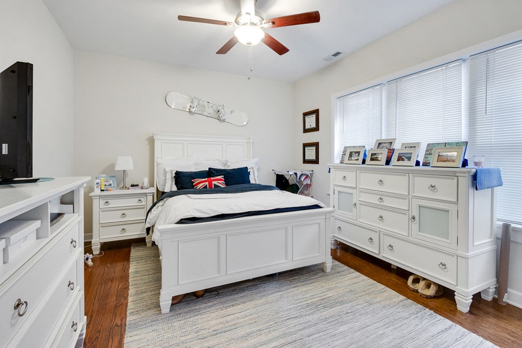 a bedroom with a bed and dressers and a ceiling fan