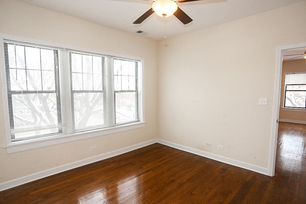 an empty living room with wood floors and a ceiling fan