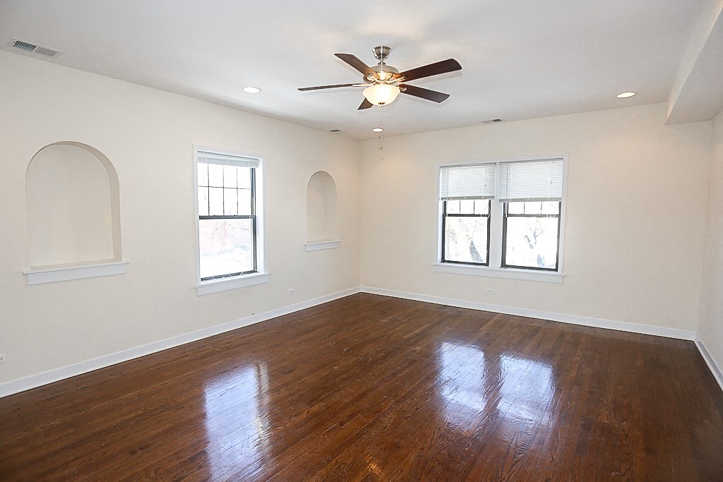 an empty living room with wood floors and a ceiling fan