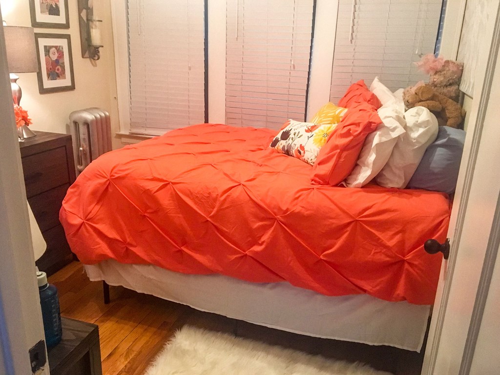 a bed with an orange comforter and many pillows on it