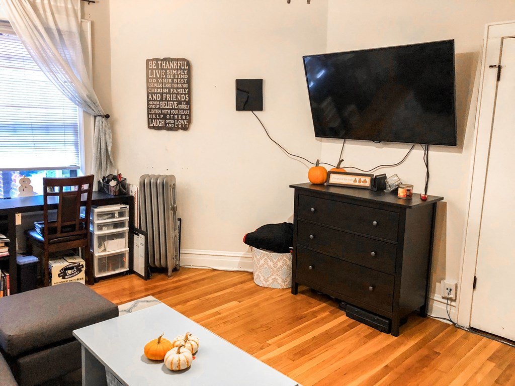 a living room with a tv on the wall and a wooden floor