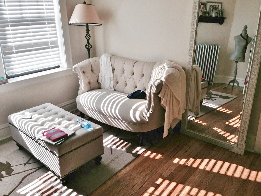 a living room with a white couch and a mirror