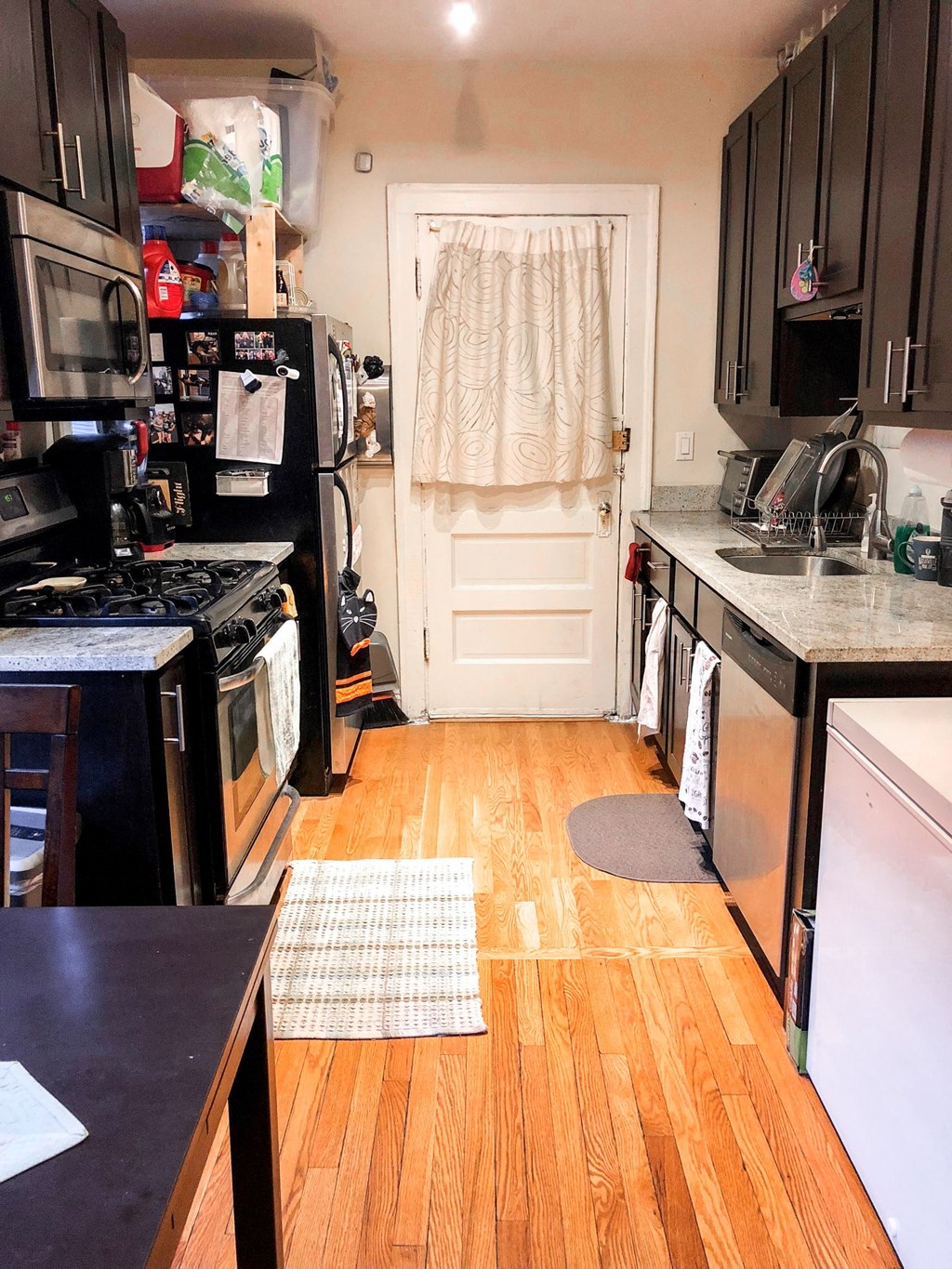 a kitchen with wooden floors and black appliances and a white door