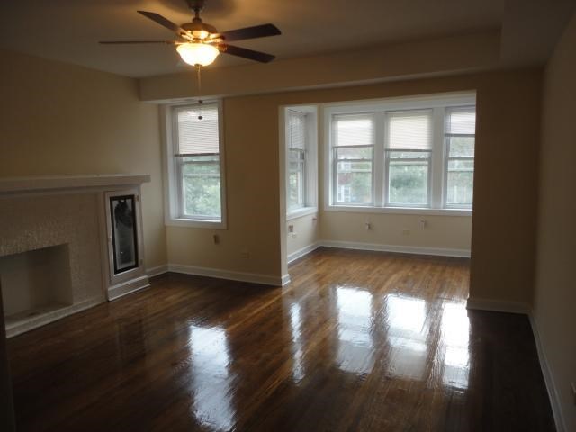 an empty living room with a ceiling fan and a fireplace