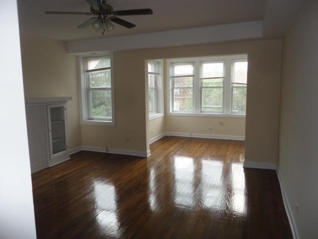 a empty living room with a ceiling fan and windows