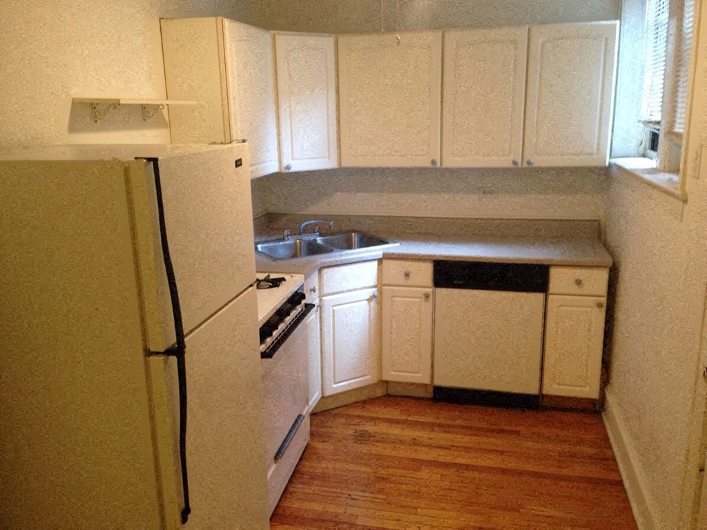 a small kitchen with white cabinets and a refrigerator