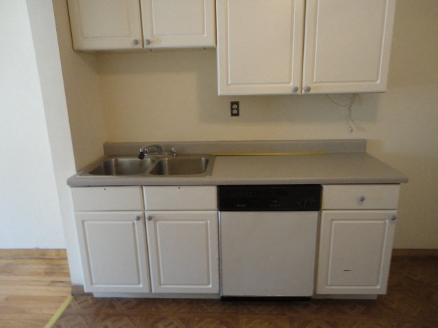 an empty kitchen with white cabinets and a sink
