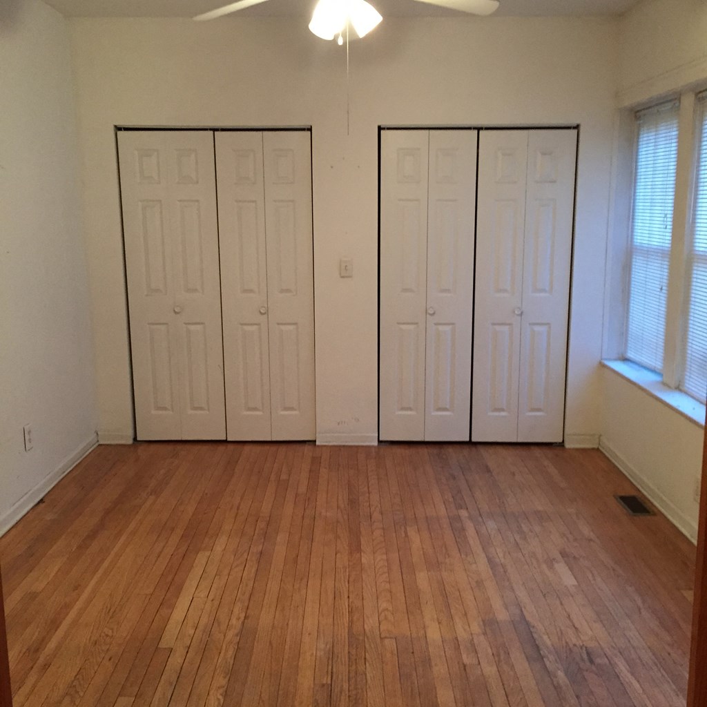 an empty living room with a wood floor and white doors