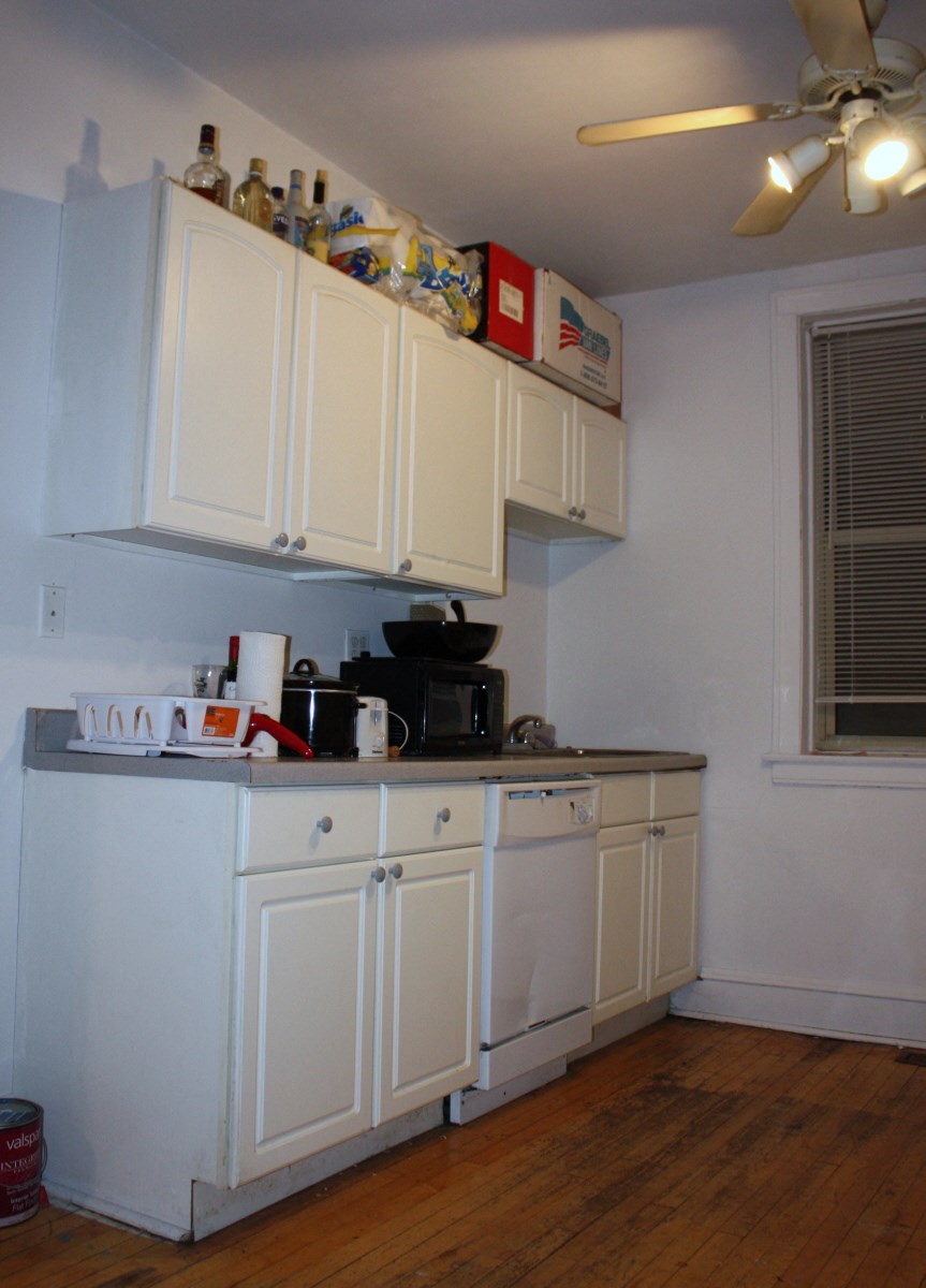 a kitchen with white cabinets and a counter top and a ceiling fan
