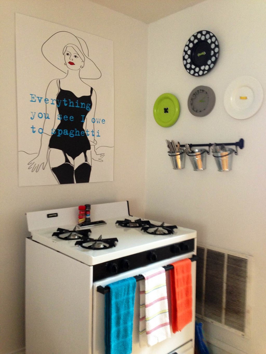 a small kitchen with a stove and a painting on the wall