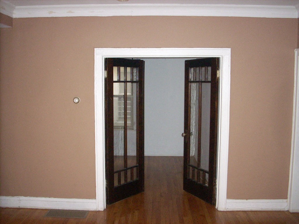 a room with two doors and a hard wood floor