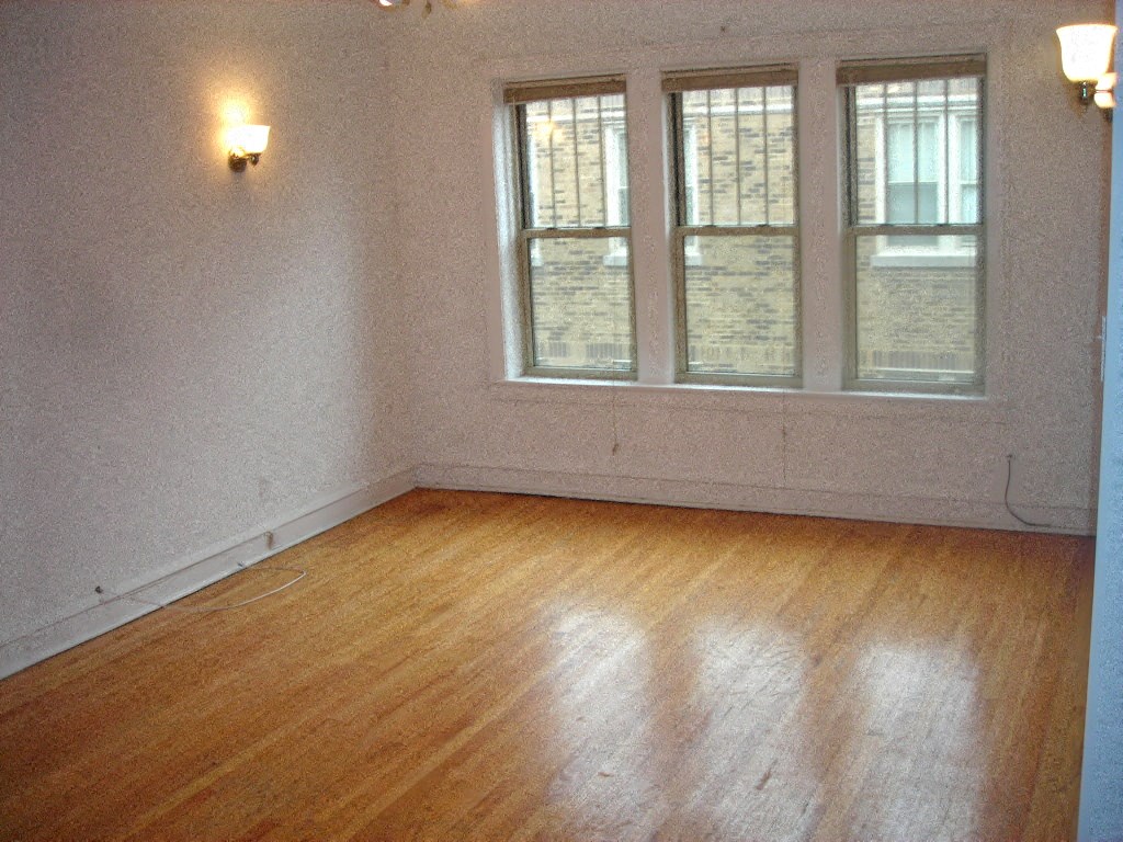an empty room with a wood floor and three windows
