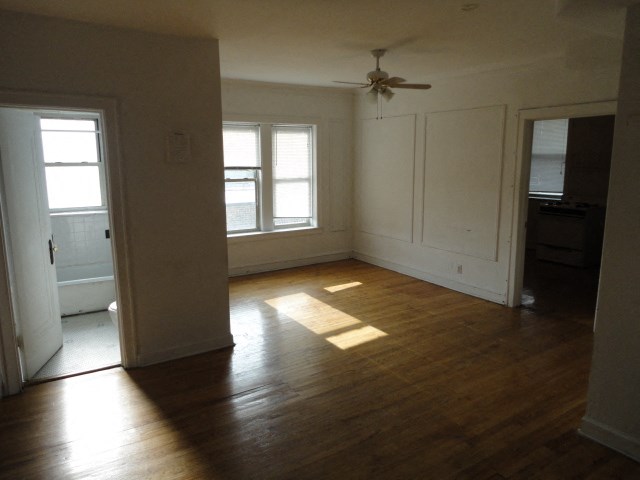 an empty living room with wood floors and a ceiling fan