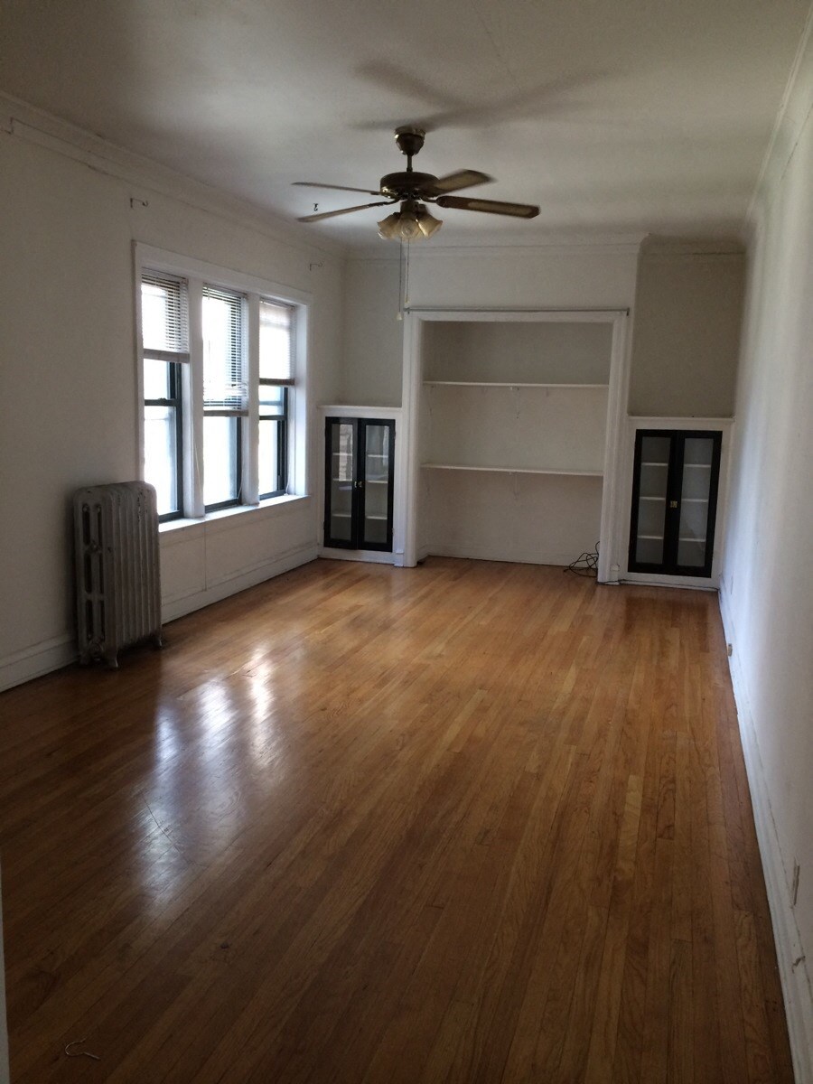 an empty living room with wooden floors and a ceiling fan