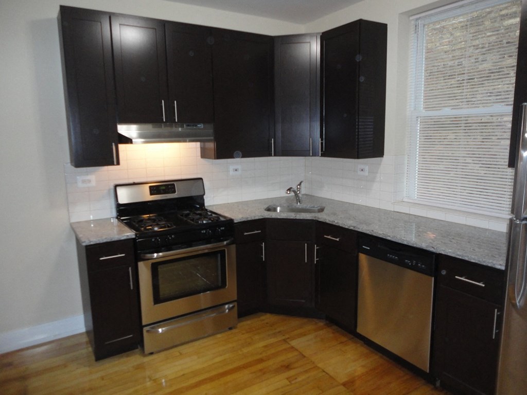 an empty kitchen with black cabinets and stainless steel appliances