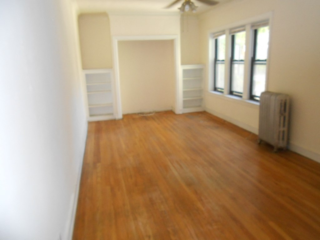 an empty living room with wooden floors and a closet