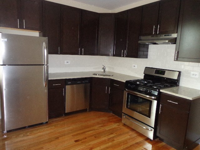 a kitchen with stainless steel appliances and a wooden floor