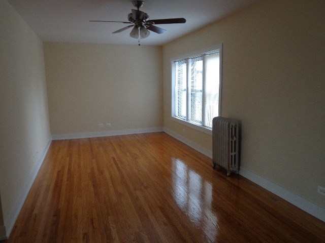 an empty room with a ceiling fan and a radiator