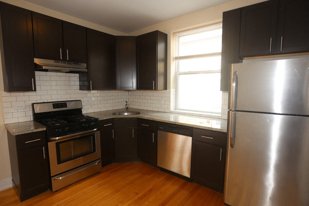 an empty kitchen with stainless steel appliances and black cabinets