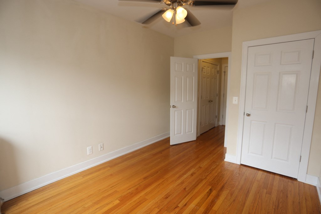 an empty living room with wood floors and a ceiling fan