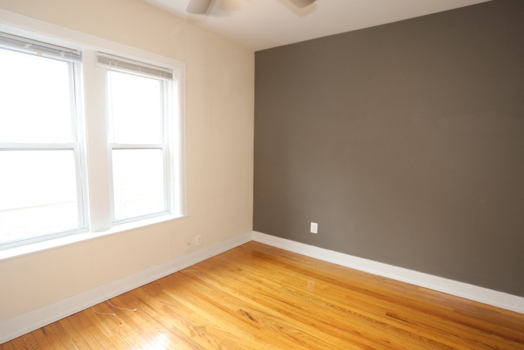 an empty room with wood floors and two windows