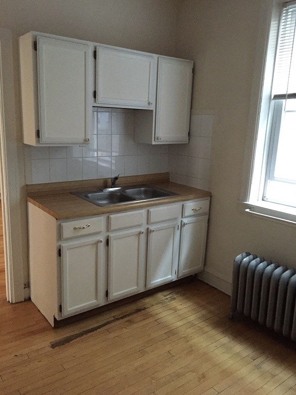 an empty kitchen with white cabinets and a sink