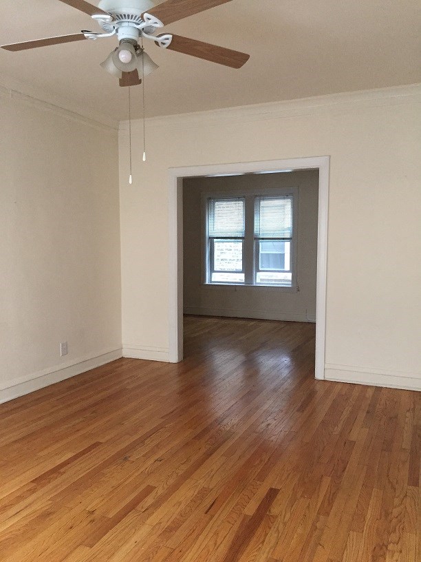 an empty living room with wooden floors and a ceiling fan