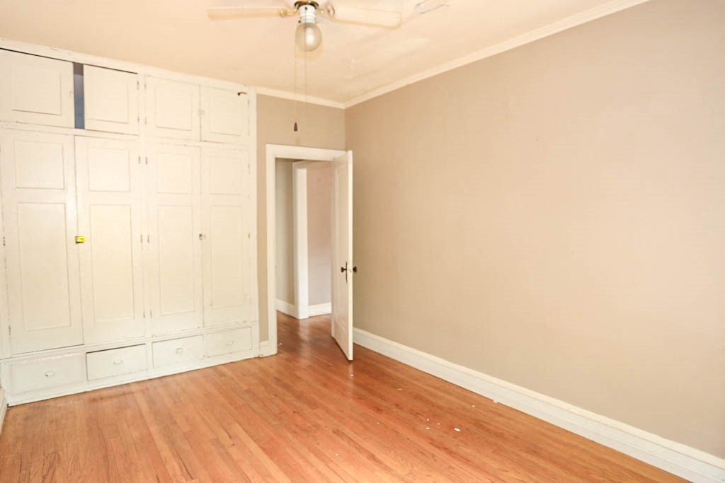 an empty living room with wood floors and white cabinets