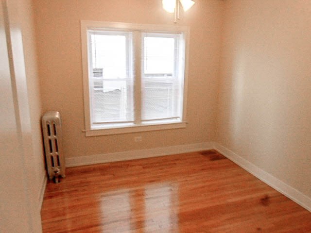 a small room with a wooden floor and two windows