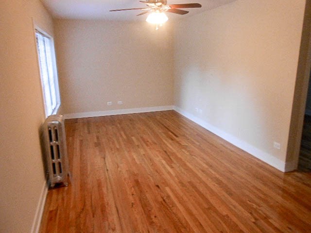 an empty room with a wooden floor and a ceiling fan