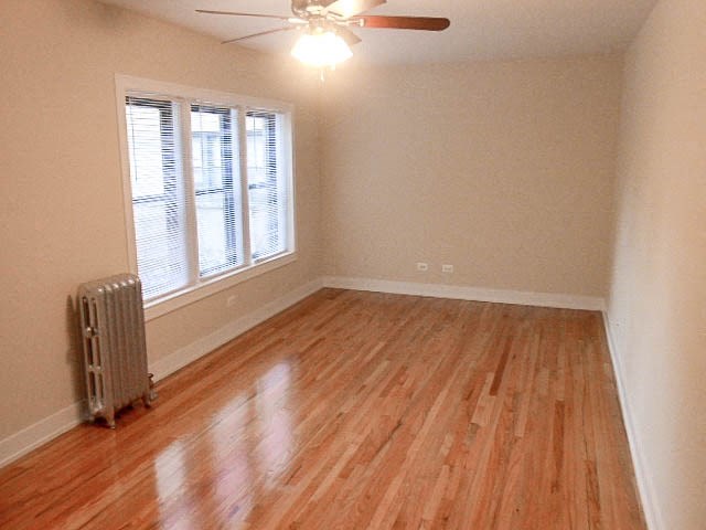 an empty living room with a wood floor and a ceiling fan