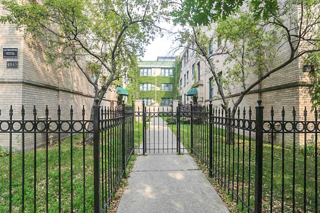a wrought iron fence in front of a sidewalk